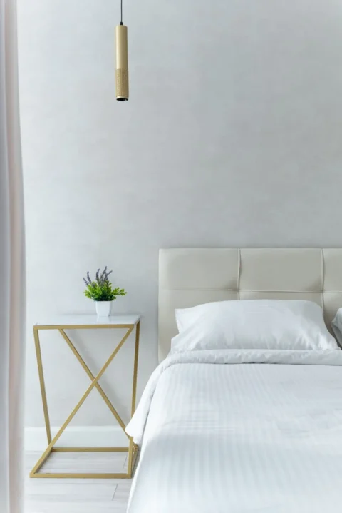 Кровать и столик с декоративным цветком в квартире с посуточной арендой в Минске